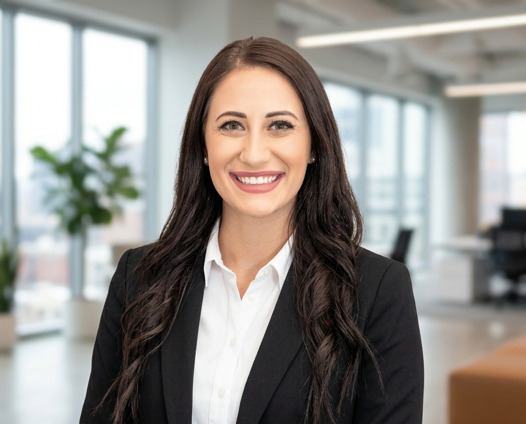 Tech employee headshot in an open-plan office with a city view, one locked company style